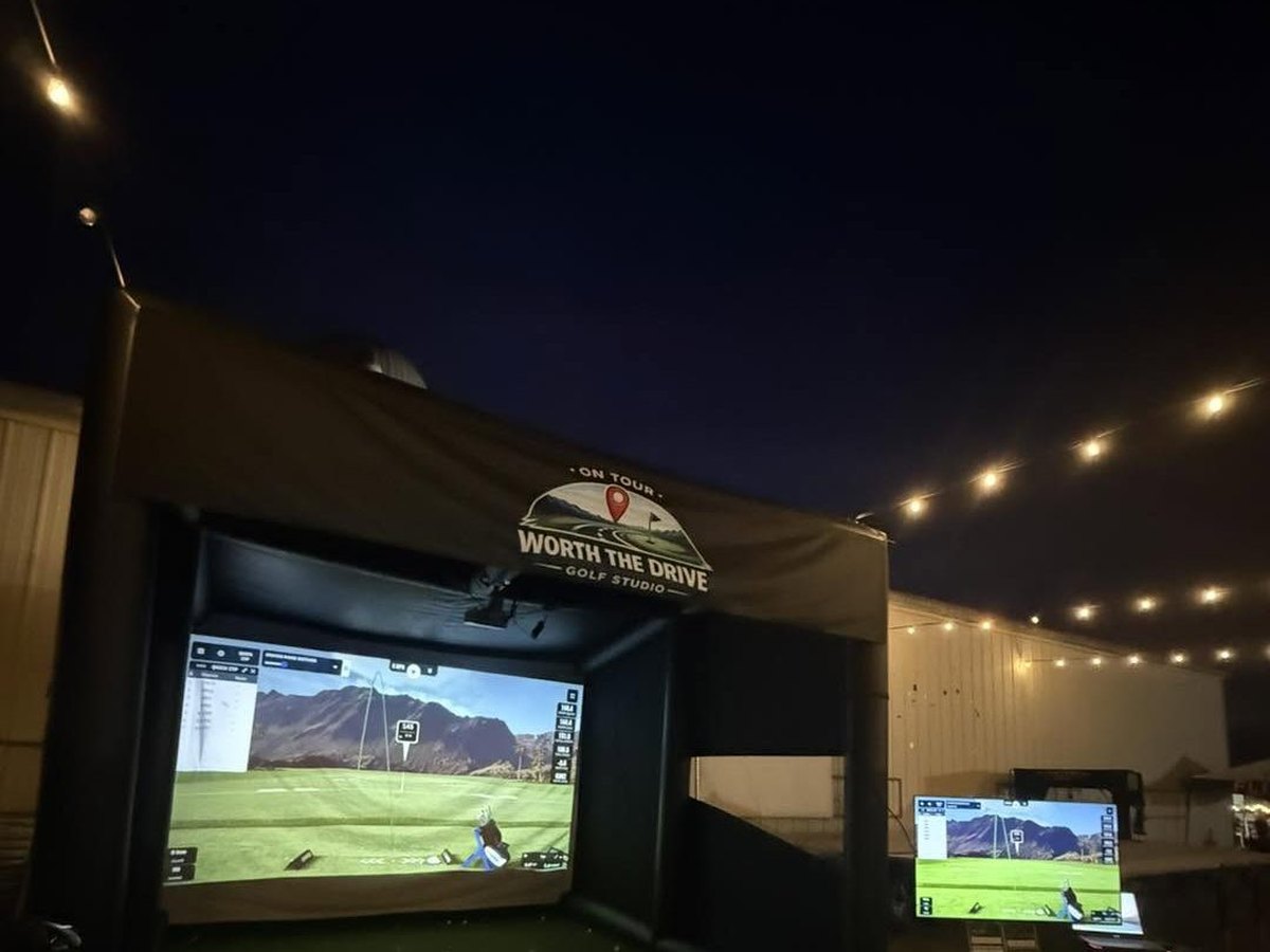 The mobile simulator enclosure lit up at night with the course on screen