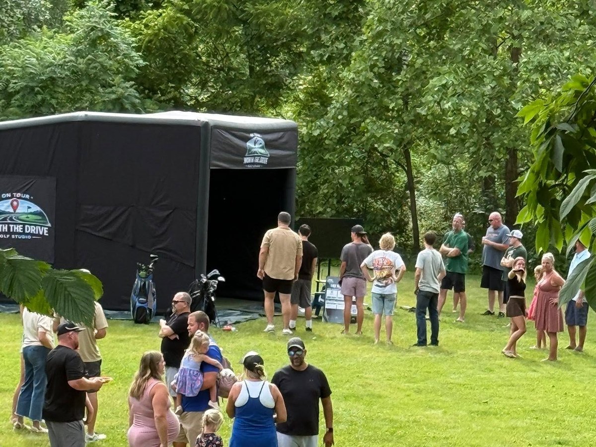 A backyard party gathered around the Worth the Drive mobile simulator